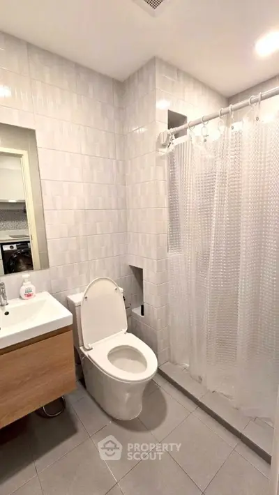 Modern bathroom with sleek fixtures and tiled walls, featuring a shower and vanity.