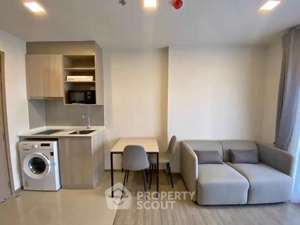 Modern living room with compact kitchen and cozy seating area in a stylish apartment.