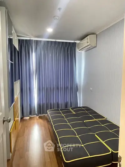 Modern bedroom with sleek design, featuring hardwood floors and air conditioning, perfect for comfort and style.