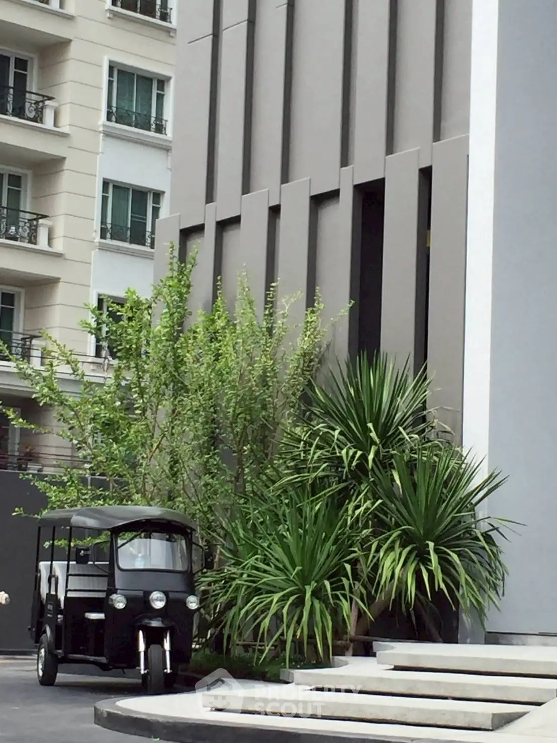 Modern building exterior with lush greenery and unique vehicle parked outside.
