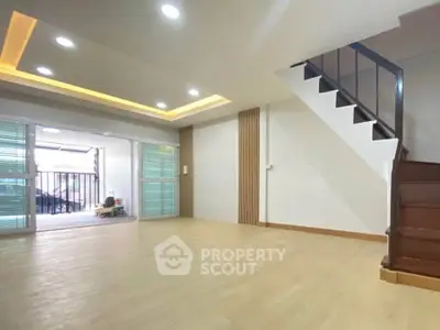 Spacious living room with modern staircase and large windows for natural light.
