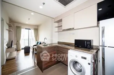 Modern open-layout kitchen with washing machine and cozy living area in stylish apartment.