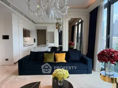 Luxurious living room with elegant chandelier and city view, featuring modern open kitchen and stylish decor.