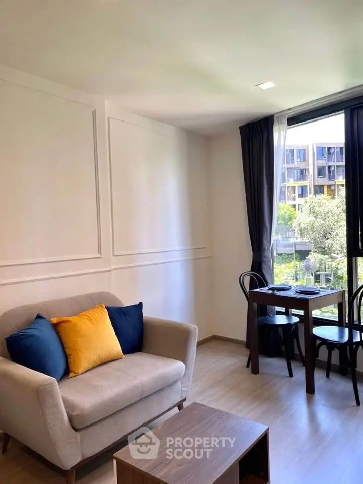 Charming living room with cozy sofa and dining area, featuring large windows with a scenic view.