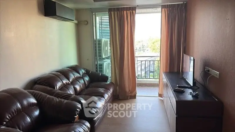 Cozy living room with leather sofa and balcony view, perfect for relaxation.