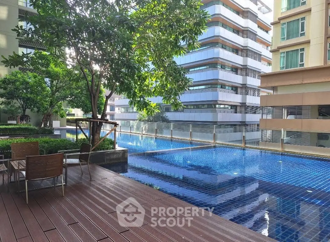 Luxurious condominium pool area with modern design and lush greenery, perfect for relaxation and leisure.