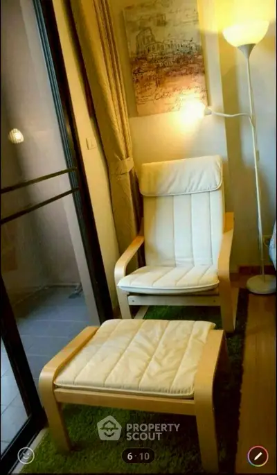 Cozy reading nook with armchair and footrest by a window, perfect for relaxation.