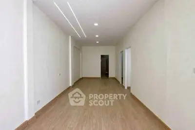Spacious empty room with wooden flooring and modern lighting, ideal for customization.