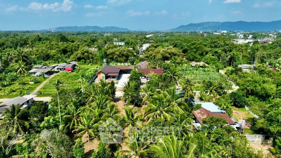 Aerial view of lush tropical landscape with houses and greenery, offering serene living environment.