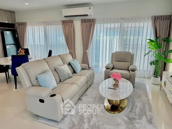 Elegant living room with plush seating and modern decor, featuring large windows and natural light.
