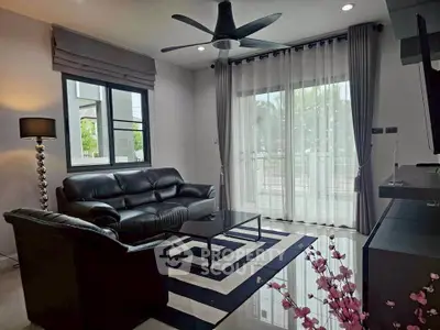 Stylish living room with leather sofas, modern decor, and large windows for natural light.