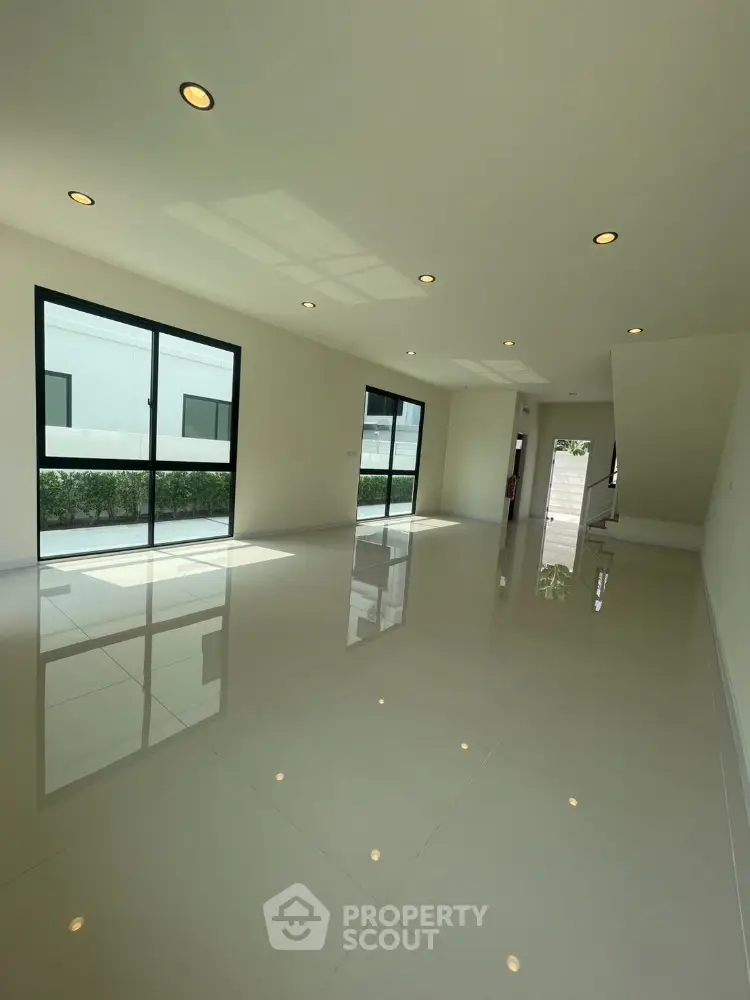 Spacious modern living room with large windows and glossy tiled floor