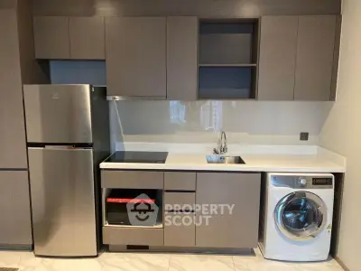 Modern kitchen with sleek cabinetry, stainless steel fridge, built-in oven, and washing machine.