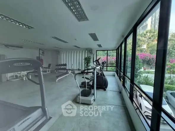Spacious gym with modern equipment and large windows offering garden views.