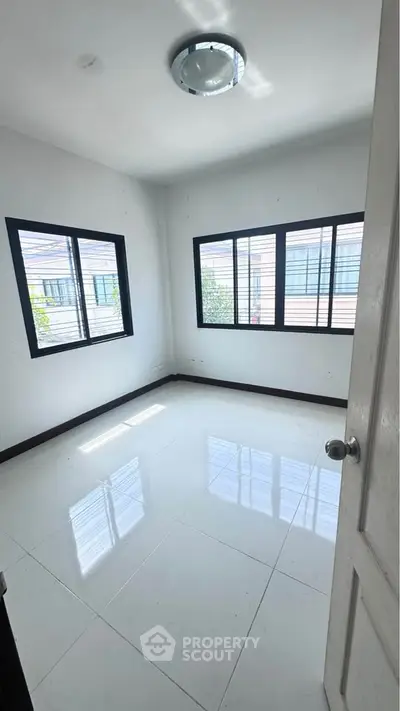 Bright empty room with large windows and glossy white tiles, perfect for customization.