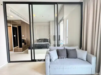 Modern apartment with glass partition separating bedroom and cozy living area.