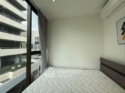 Modern bedroom with large window and city view, featuring a comfortable bed and air conditioning.