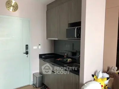 Compact kitchen with modern cabinetry and microwave in cozy apartment.