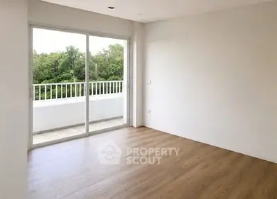 Spacious empty room with large sliding glass doors leading to a balcony with lush green views.