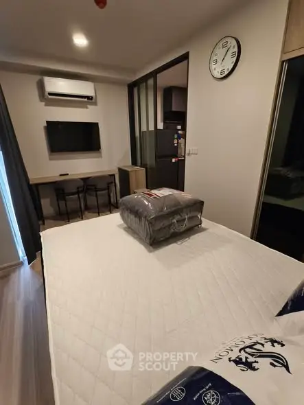 Modern bedroom with stylish decor, featuring a wall-mounted TV, air conditioning, and a cozy workspace.