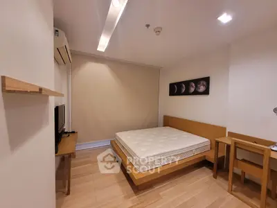 Modern minimalist bedroom with wooden flooring and sleek furniture design.