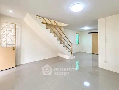 Spacious modern living room with sleek staircase and glossy tiled floor