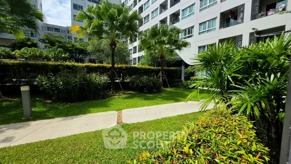 Lush garden view in modern residential complex with palm trees and manicured lawns.