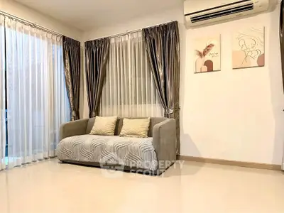 Elegant living room with modern sofa and stylish curtains, featuring wall art and air conditioning.