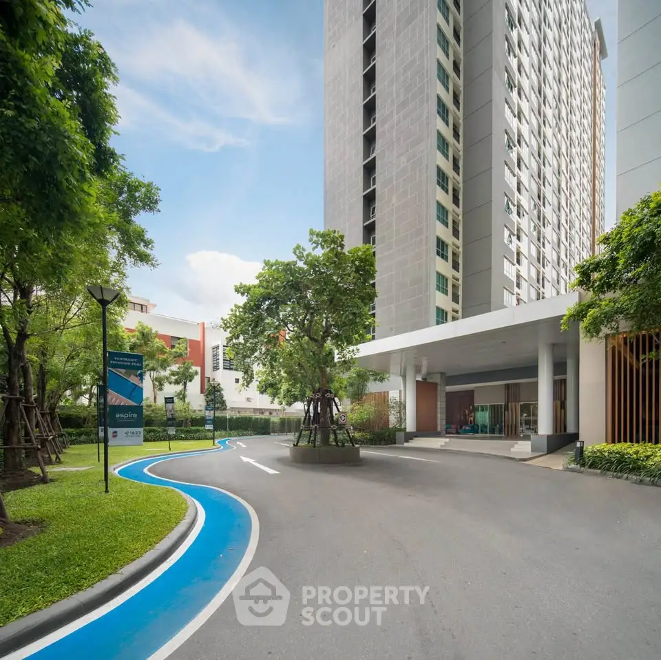 Modern high-rise building with lush green landscaping and sleek entrance.
