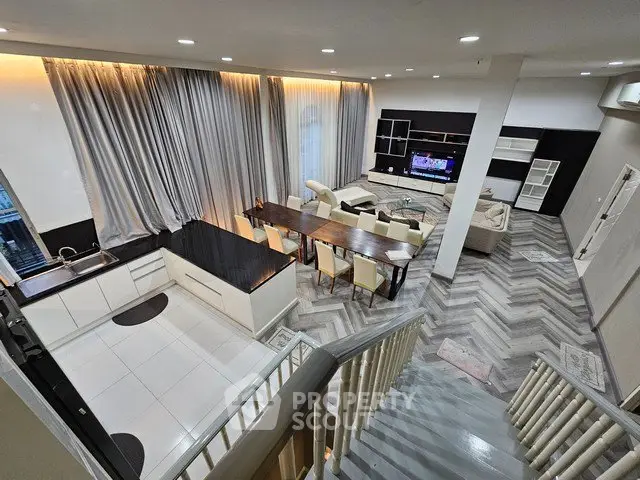 Spacious modern living room with open kitchen and elegant dining area, featuring stylish flooring and high ceilings.