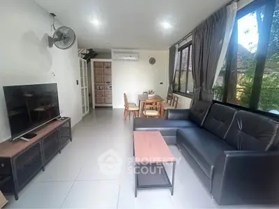 Spacious living room with modern furniture and large windows offering garden views.