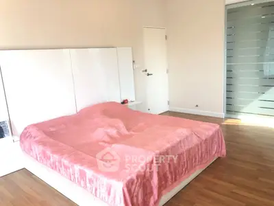 Spacious bedroom with modern design and pink bedding in bright natural light.