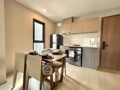 Modern kitchen with dining area, featuring sleek cabinetry and integrated appliances in a stylish apartment.