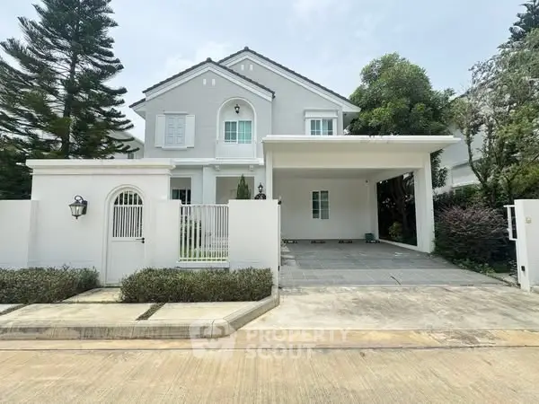 Charming two-story white house with spacious driveway and lush greenery