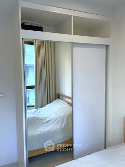 Modern bedroom with mirrored closet and cozy bed, perfect for urban living.