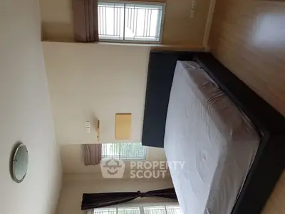 Spacious bedroom with large windows and modern bed frame, offering ample natural light.