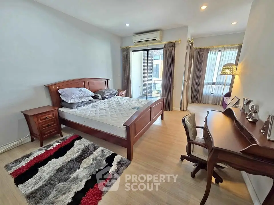 Spacious bedroom with elegant wooden furniture and balcony access in modern apartment.