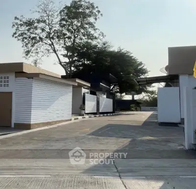 Modern residential complex with sleek architecture and spacious driveways, surrounded by lush greenery.
