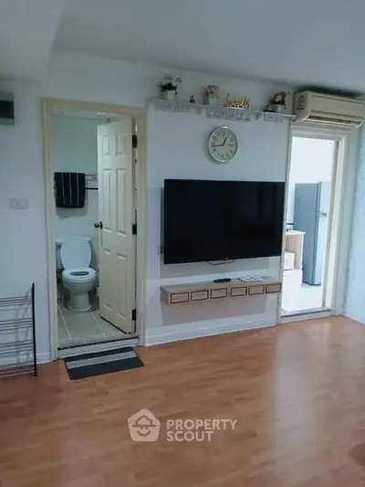 Cozy living room with wall-mounted TV and adjacent bathroom in modern apartment.