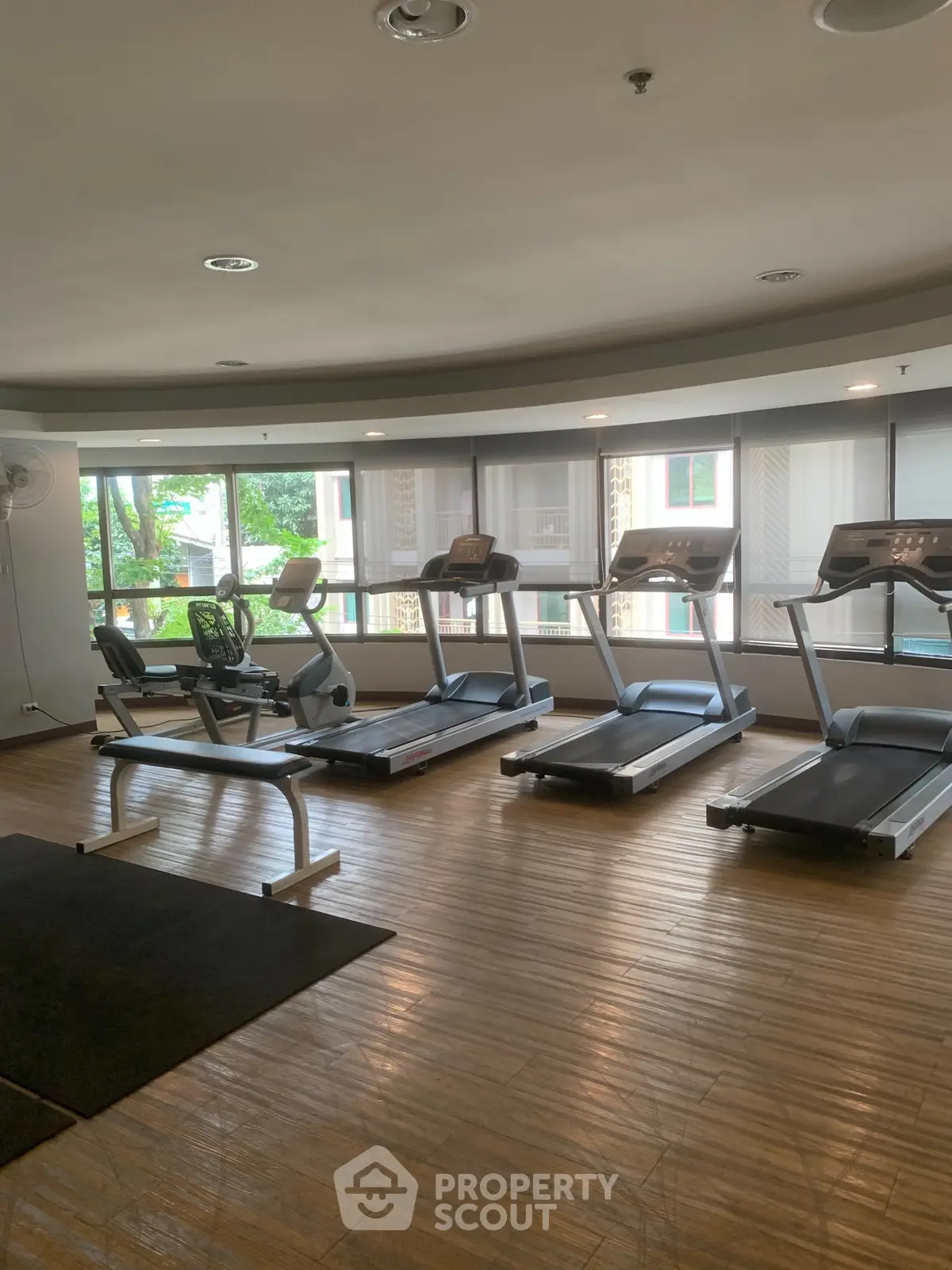 Spacious gym with modern treadmills and large windows offering natural light.