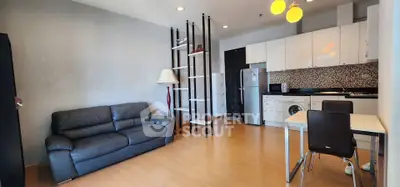 Modern open-plan living room with sleek kitchen, leather sofa, and stylish shelving in a contemporary apartment.