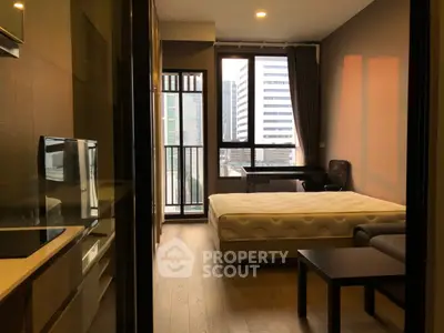 Modern studio apartment with city view, featuring a cozy bed, sleek furniture, and large windows for natural light.