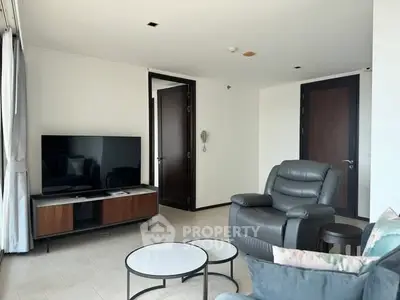 Spacious modern living room with sleek furniture and large TV, perfect for relaxation.