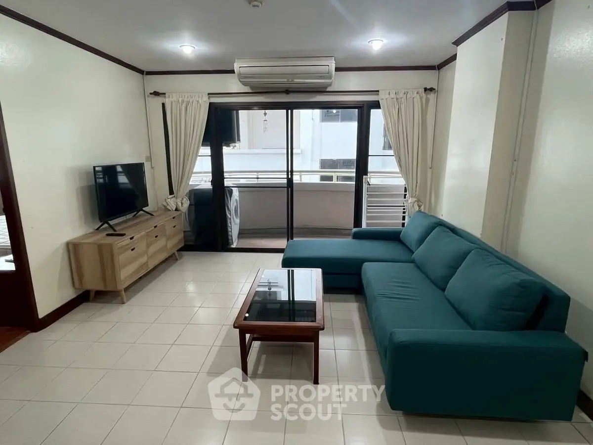 Spacious living room with modern teal sofa and large TV, perfect for relaxation.