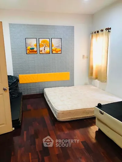 Cozy bedroom with wooden flooring and modern decor, featuring a mattress and stylish wall art.