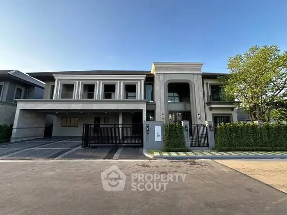 Luxurious modern house exterior with spacious driveway and lush greenery.