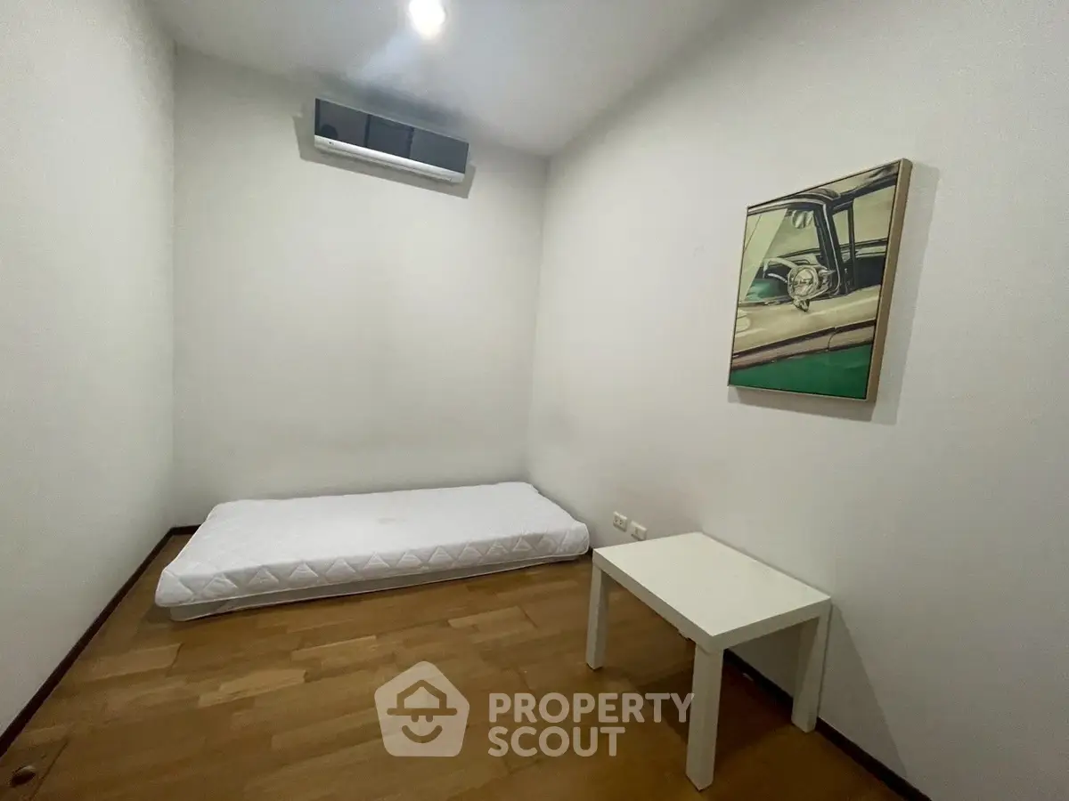 Minimalist bedroom with mattress and table on wooden floor