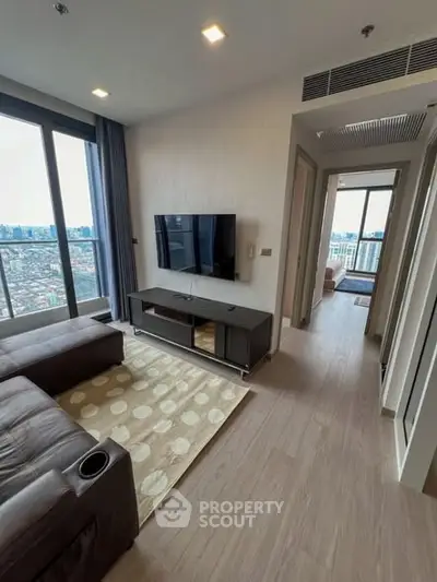Modern living room with city view, featuring sleek furniture and large windows for natural light.