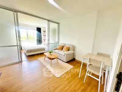 Bright and airy studio apartment with sliding glass doors and cozy furnishings.
