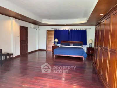 Spacious bedroom with wooden flooring and elegant furnishings